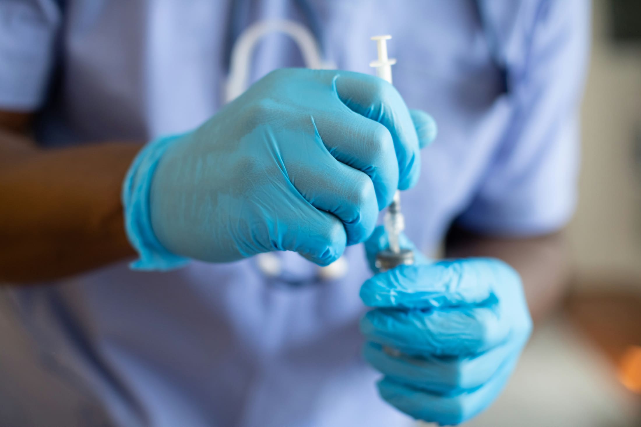 Gloved medical provider preparing an injectable treatment syringe